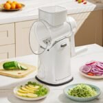 Hand crank rotary drum grater machine slicing vegetables like cucumber and onion in kitchen