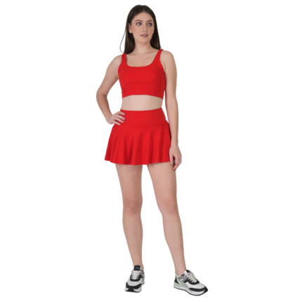 Woman wearing red tennis skirt and crop top athletic outfit for workout golf yoga and sports